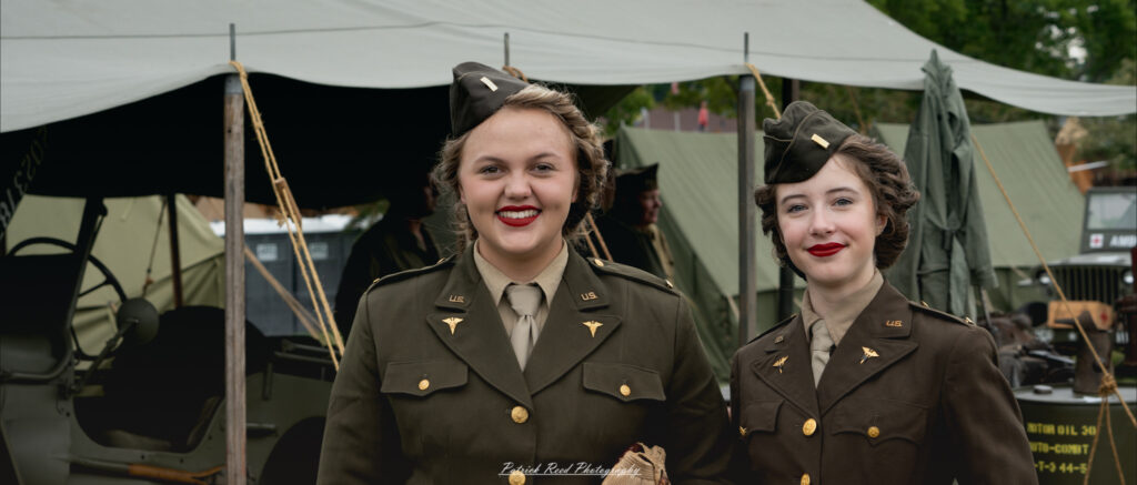 Two army nurses smiling together, dressed in their uniforms. Their expressions radiate warmth and camaraderie, capturing the spirit of teamwork and dedication in providing care to soldiers during their service.
